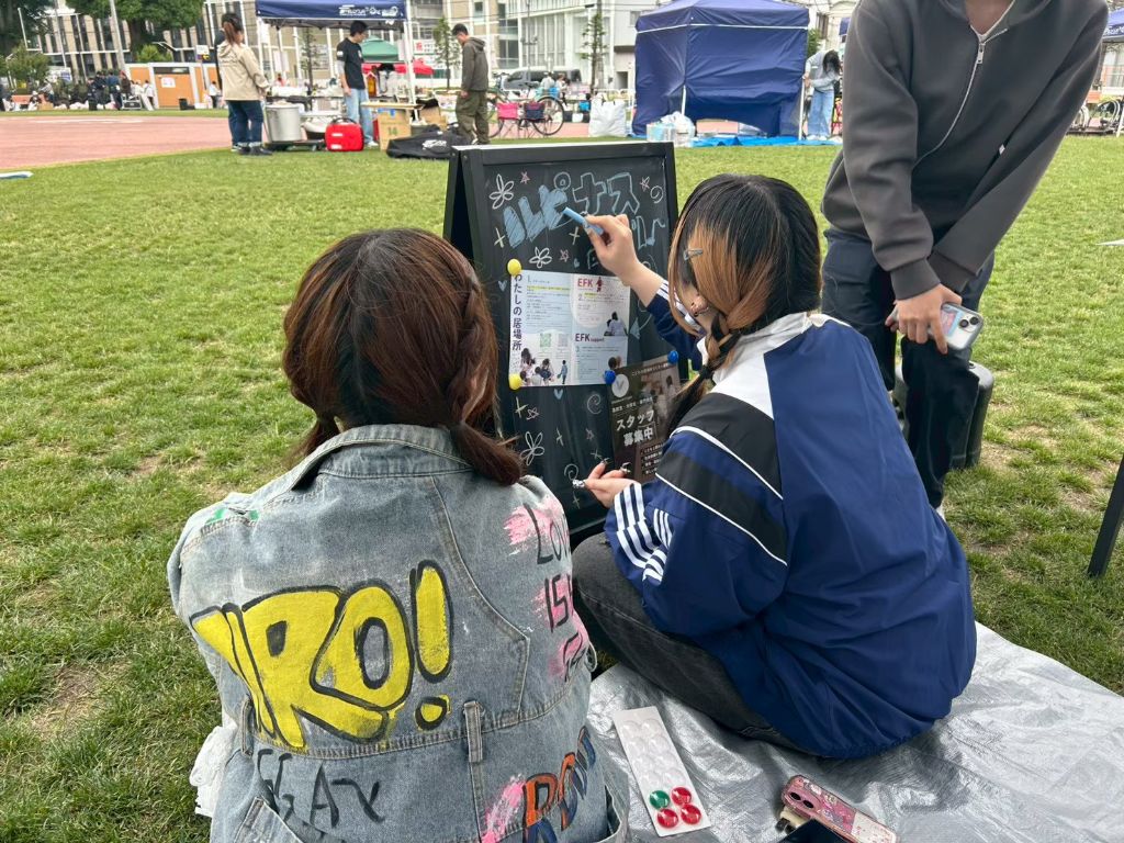 出展ブースの看板を書く学生スタッフ