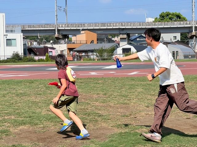 学生スタッフとこどもが外で走り回る様子