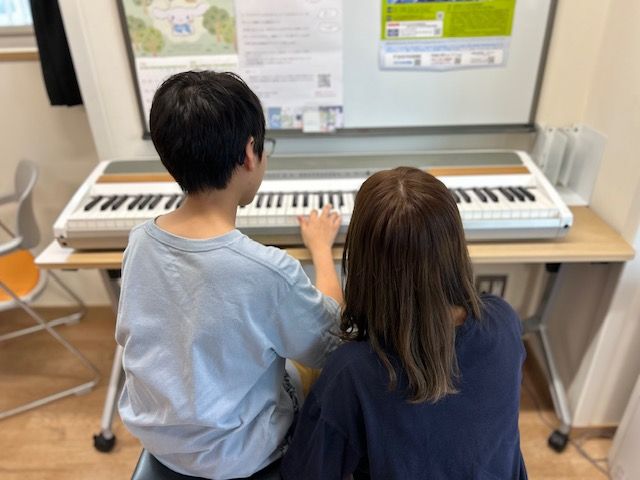 こどもと学生がピアノを弾く様子