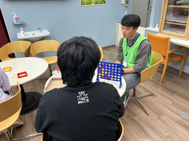 学生スタッフとこどもが4目並べで遊ぶ様子