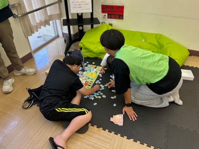 学生スタッフとこどもがパズルをする様子